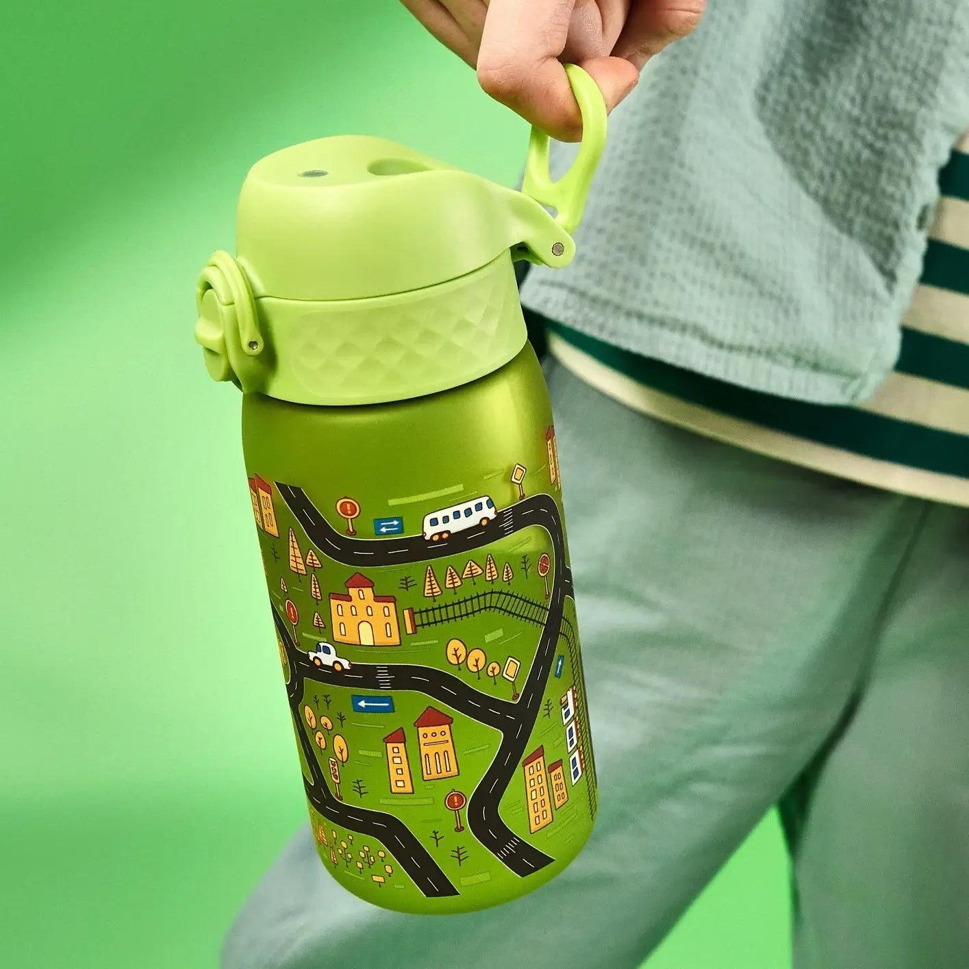 A green metal water bottle, featuring a city-themed design, is held by a person against a green background.