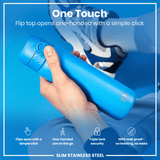 A blue, slim stainless steel water bottle is being held; its flip top opens one-handed via a simple click; it's shown against a blue background with a blurred-out person's lower body and shoes.
