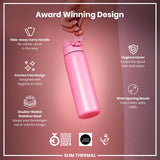 A pink, double-walled stainless steel water bottle is held by a hand. Its features include a hide-away carry handle, crevice-free design, hygiene cover, and wide opening mouth. It's an award-winning design.