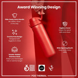 A red, double-walled stainless steel water bottle is held by a hand against a red background. Its features include a hide-away handle, crevice-free design, hygiene cover, and wide opening mouth. The bottle is a 2024 German Design Award winner.