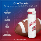 A slim stainless steel water bottle, featuring a flip top that opens one-handedly, rests beside an American football. The bottle's design incorporates the Tampa Bay Buccaneers logo. 