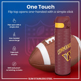 A maroon water bottle, featuring a one-touch flip top and a Washington Commanders design, sits near an American football against a dark background. 