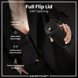 A black water bottle with a full flip lid is held by a person wearing black clothing. The lid opens 240 degrees, sits away from the face, and provides a clear line of sight. It is advertised as perfect for on-the-go drinking. SLIM RECYCLON™