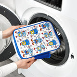 Hands are placing a colorful pouch decorated with blue robots into an open front-loading washing machine in a bright laundry room.