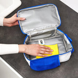 Hands cleaning a blue lunch bag with a yellow sponge on a dark countertop context with visible white label text ION8 inside the bag