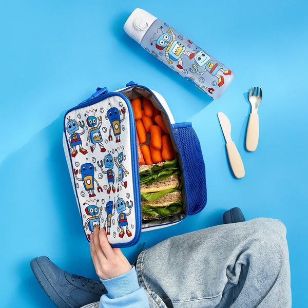 Lunchbox with robot designs containing carrots and sandwiches opened by a hand on a blue surface includes matching water bottle and utensils nearby jeans visible in corner