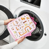 A person places a pink pet-themed zippered pouch with animal illustrations into a front-loading washing machine in a laundry room setting.