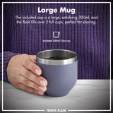 A hand holds an insulated blue mug filled with liquid on a marble surface. Text reads 