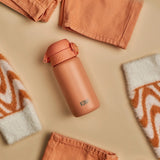 A peach-colored water bottle labeled 