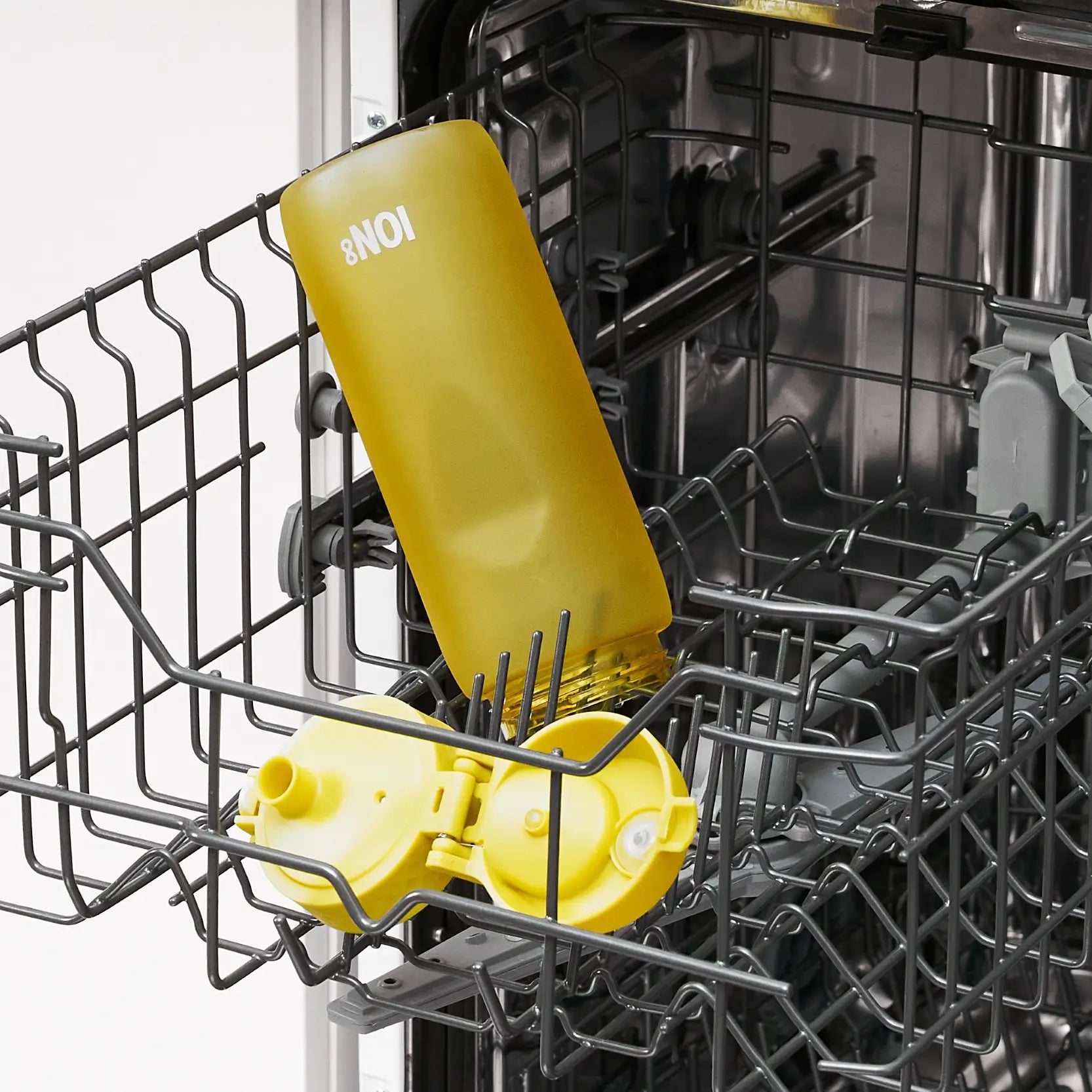 A yellow water bottle, labeled "8 NOI," is being cleaned inside a dishwasher's wire rack.