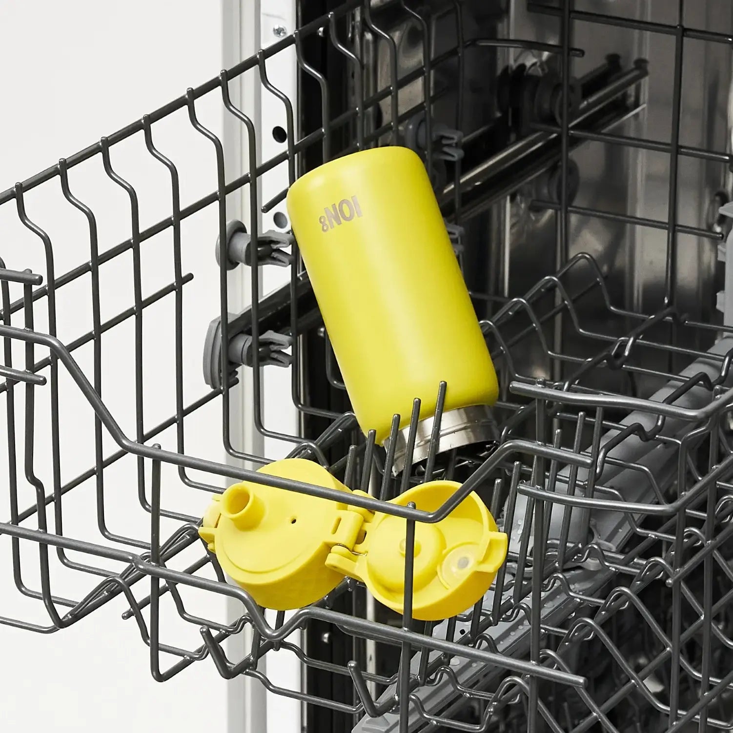 A yellow ION8 water bottle is being washed inside a dishwasher's top rack.