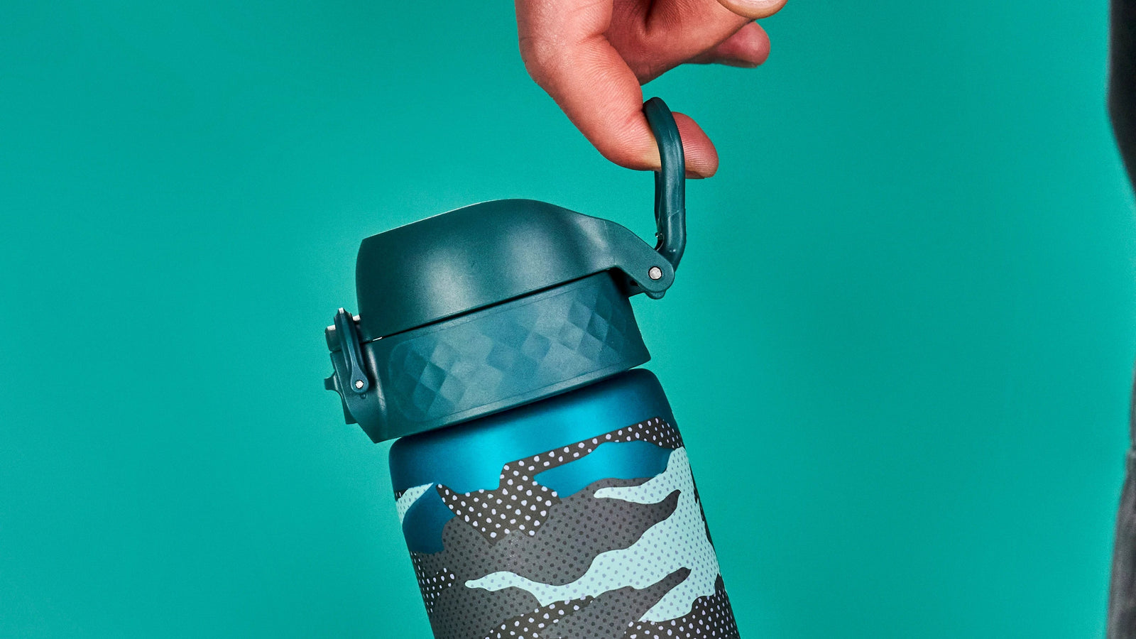 A hand opens a teal and camouflage water bottle's lid against a teal background.