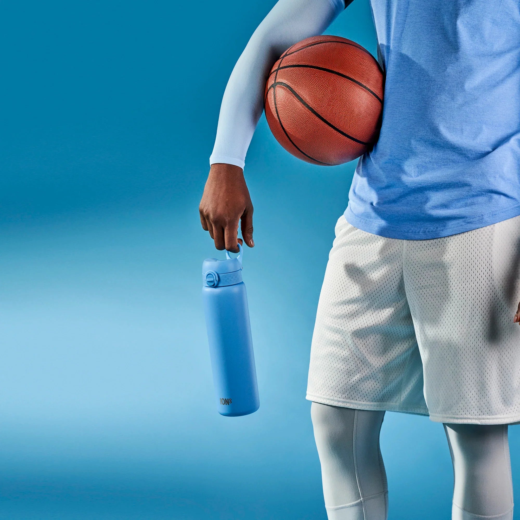 A person holds a blue ION8 water bottle; they are also holding a basketball against their side, wearing athletic clothing against a blue background.